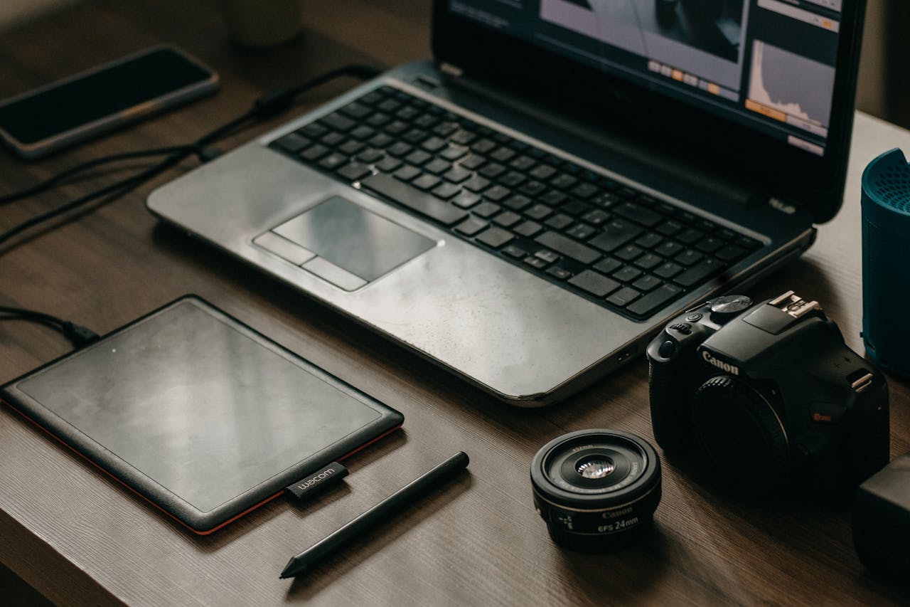 Services-03 Laptop, camera, lens, and graphic tablet on a desk for digital creatives.