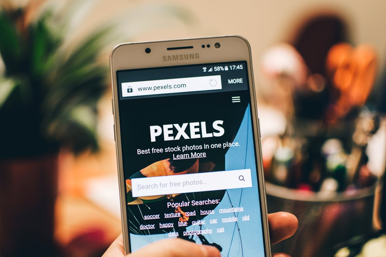 mobile-02 A close-up view of a smartphone displaying the Pexels website screen for stock photo searches.